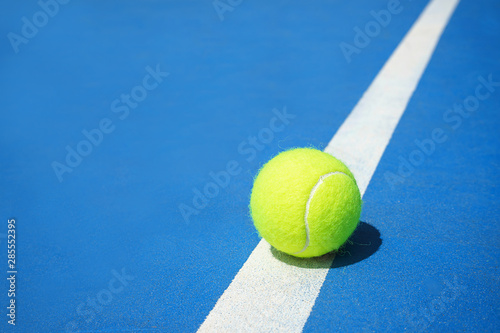 Summer sport concept with tennis ball on white line on hard tennis court blue color. © IrynaV