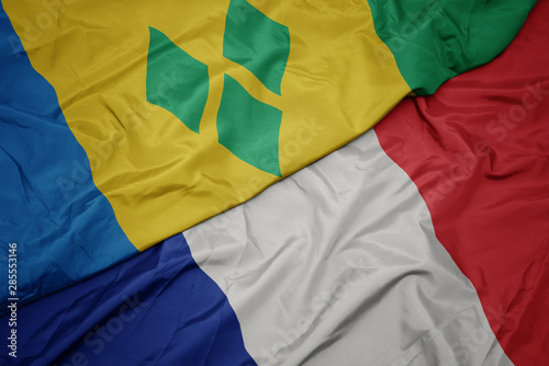 waving colorful flag of france and national flag of saint vincent and the grenadines.