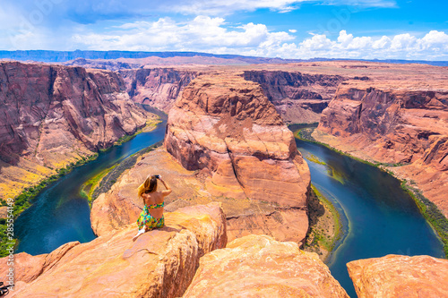 Young tourist girl with green dress at Horseshoe Bend taking a picture, Arizona. United States