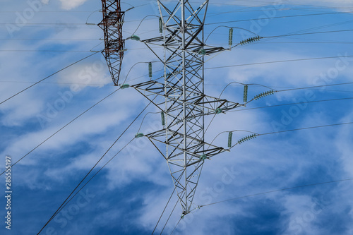 Supports high-voltage power lines against the blue sky with clouds. Electrical industry photo