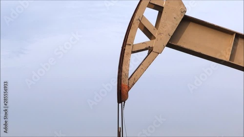 Industrial oil derrick pumping with palm trees in background