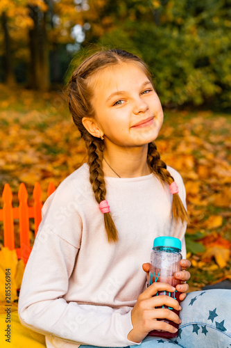 blonde girl child outrods in the country autumn forest. happy emotional child with an eco bouttle with juice photo