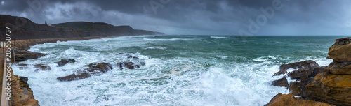 A huge ocean waves breaking on the coastal cliffs in at the cloudy stormy day. Breathtaking romantic panoramic seascape of ocean coastline. Peniche, Portugal. © Sodel Vladyslav