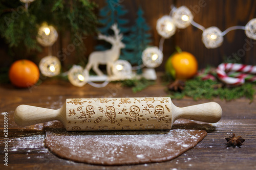 Rolled dough with rolling pin on wooden table covered with baking flour.