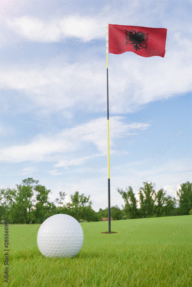 Obraz premium Albania flag on golf course putting green with a ball near the hole