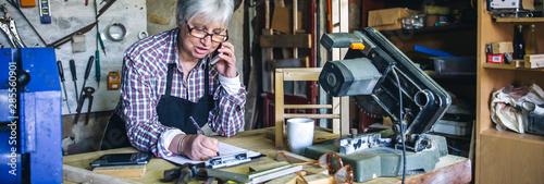 Senior female carpenter talking on the phone in her workshop