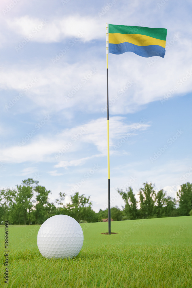 Obraz premium Gabon flag on golf course putting green with a ball near the hole