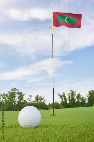 Maldives flag on golf course putting green with a ball near the hole