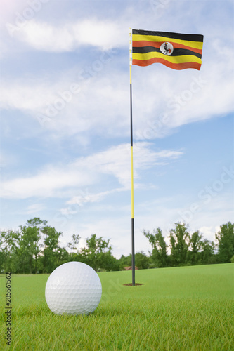 Uganda flag on golf course putting green with a ball near the hole