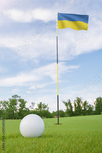Ukraine flag on golf course putting green with a ball near the hole