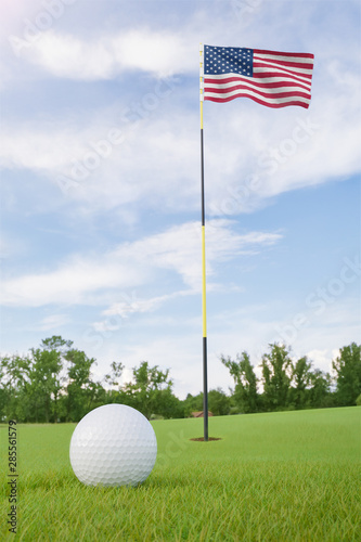 United States flag on golf course putting green with a ball near the hole