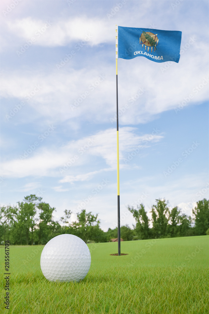 Obraz premium Oklahoma flag on golf course putting green with a ball near the hole