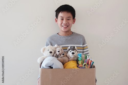 Photography Mixed Asian young volunteer preteen teenage boy holding a box full of used toys,