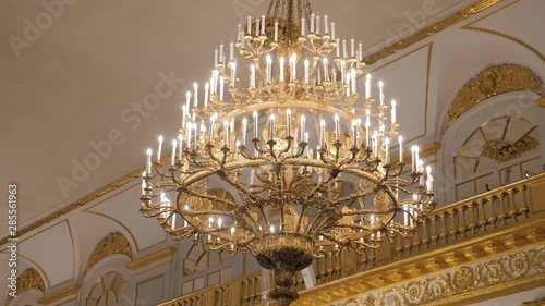Beautiful large crystal chandelier in a royal environment. Interior elements - decorated ornate ceiling large luxury Golden chandelier.