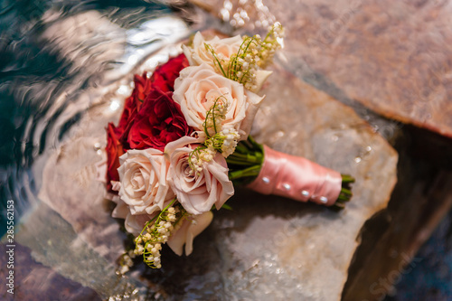 A bouquet of red and pink roses sitting on cut stone and water. photo