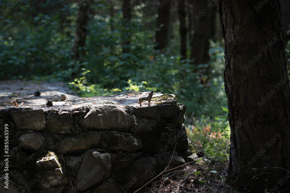 Howling wolf in the forest. Mini wolf figure standing on the forest ground. Howling wolf in the forest. Mini wolf figure standing on the forest ground.