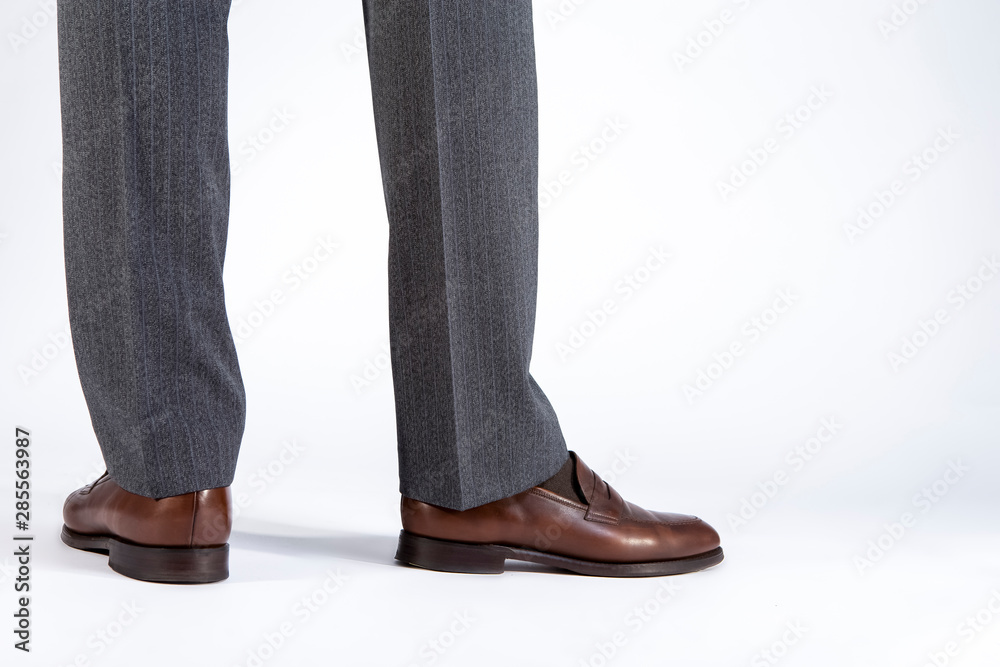 Back View of Mens Legs Wearing Brown penny Loafers. Against White Background.