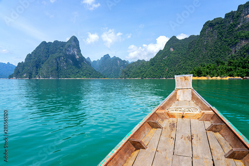 Wooden boat in green lake with limestone mountain range background