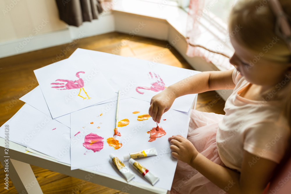 Portrait of a cute little girl painting hands at home. Learn, education, happy childhood concept Portrait of a cute little girl painting hands at home. Learn, education, happy childhood concept