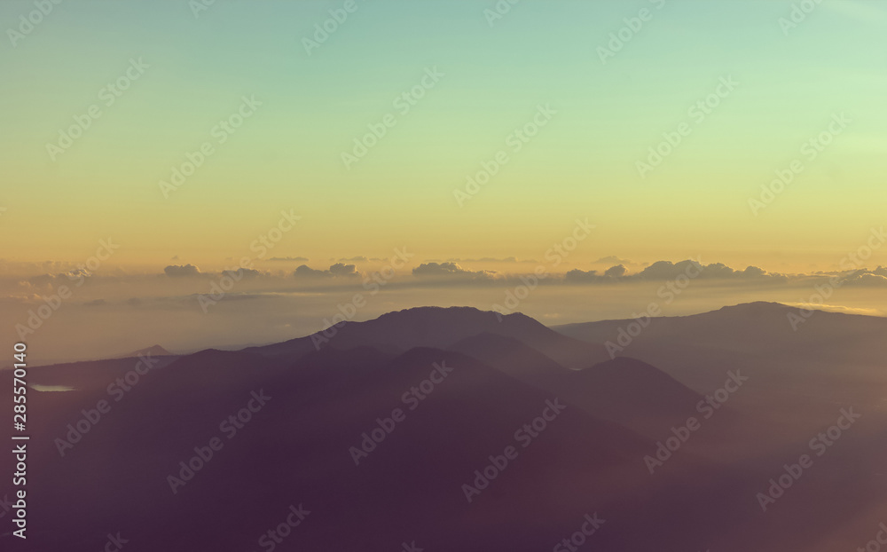 Mountains on the horizon view from a plane at sunrise with the colors of the sky and the shapes of the mountains