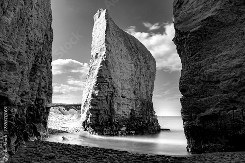 Dreamy tranquility concept with atmospheric monochrome photograph of iconic chalk steep cliff and long exposure of wave flow creating silky fine mist in Botany Bay, Broadstairs, Kent, United Kingdom