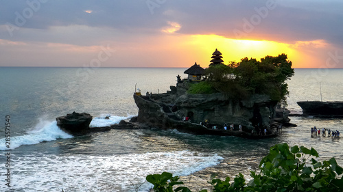 Valokuva tourists wading out to tanah lot temple at sunset