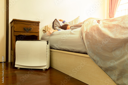 Air purifier in the bed room with young boy stretching on the bed.