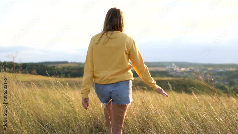 Young woman in yellow sweatshirt walking in a field Young woman in yellow sweatshirt walking in a field