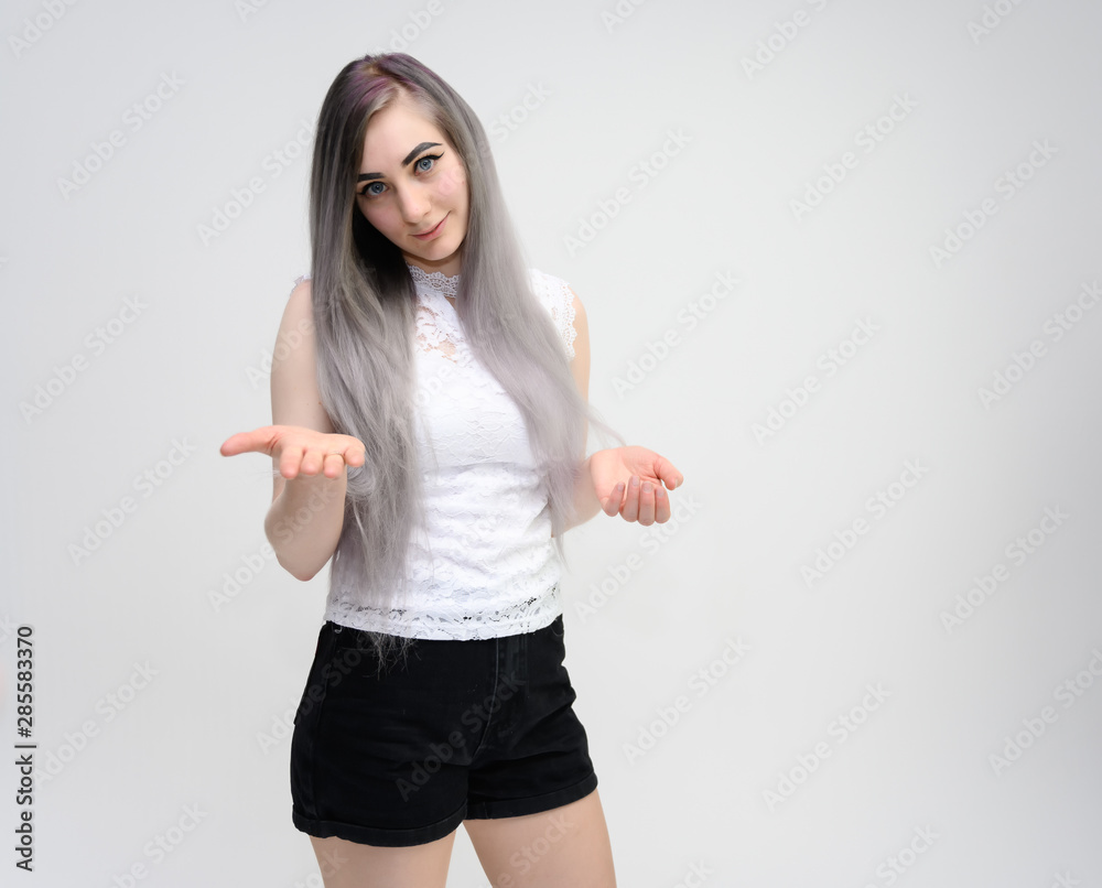 Studio portrait on the waist of a pretty manager girl with long beautiful hair in a white T-shirt and black shorts on a white background. He stands straight, smiles, shows with his hands. Studio portrait on the waist of a pretty manager girl with long beautiful hair in a white T-shirt and black shorts on a white background. He stands straight, smiles, shows with his hands.