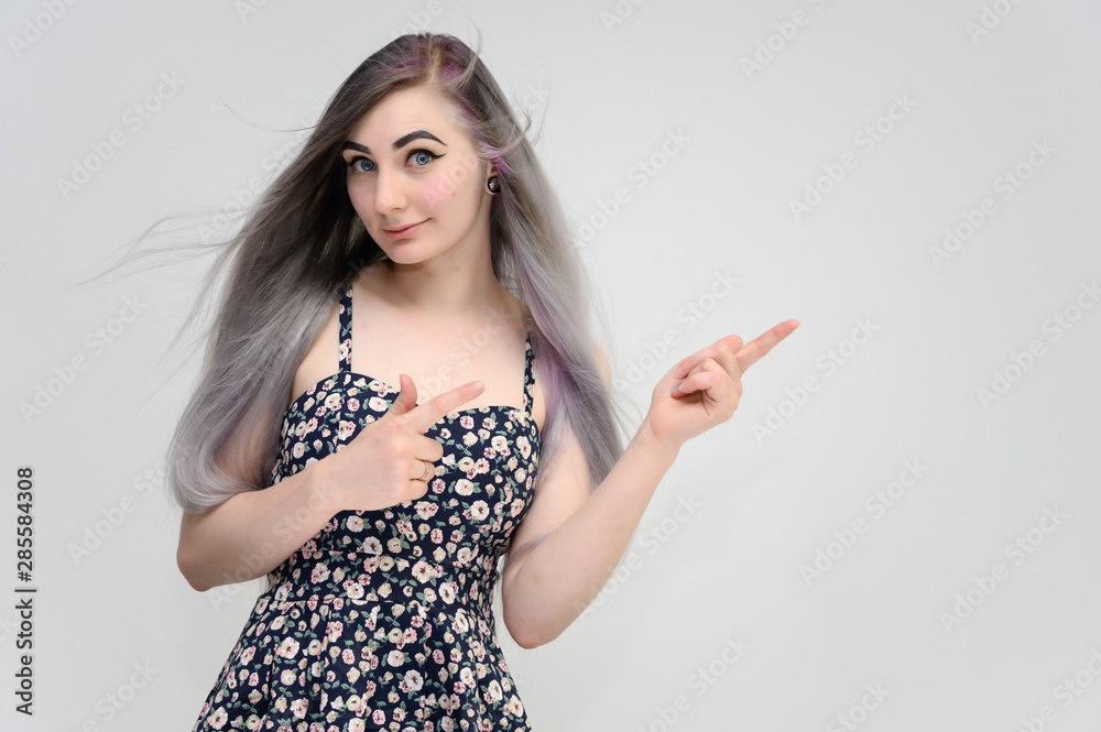 Studio portrait on the waist of a pretty manager girl with long beautiful hair in a beautiful color dress on a white background. He stands straight, smiles, shows with his hands. Studio portrait on the waist of a pretty manager girl with long beautiful hair in a beautiful color dress on a white background. He stands straight, smiles, shows with his hands.