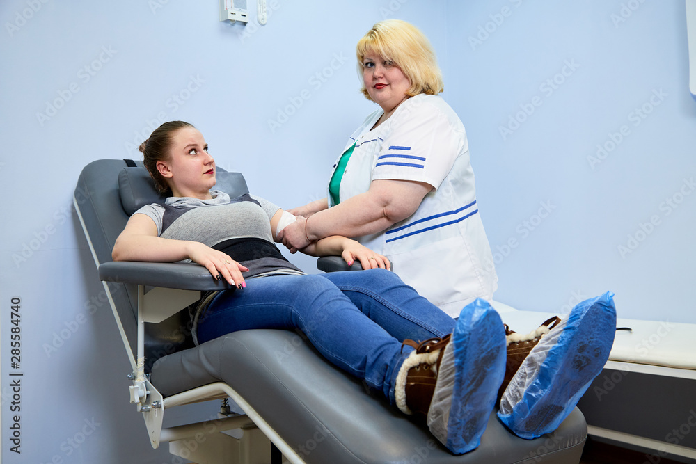 Obraz premium Experienced doctor fat woman taking care of a sick girl on the couch in the medical office