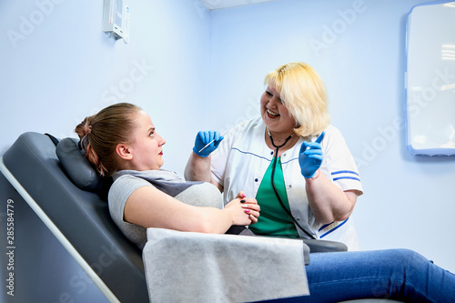 Experienced doctor fat woman taking care of a sick girl on the couch in the medical office