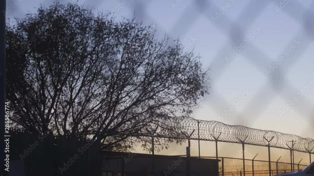 Prison Fence At Sunset Through Razor Wire Prison Fence At Sunset Through Razor Wire