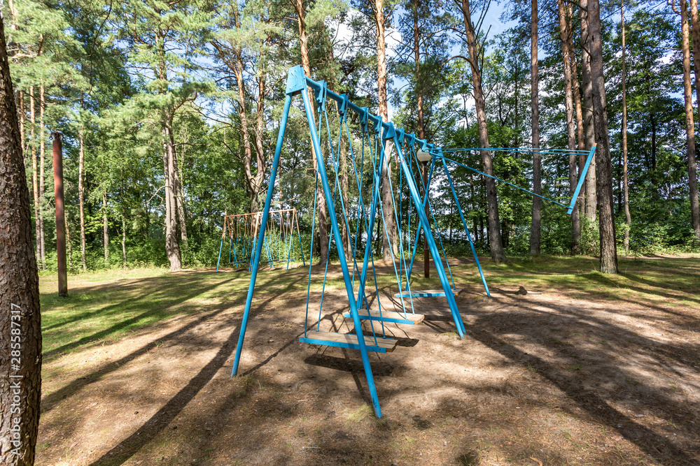 swing and horizontal bars on playground in pine forest