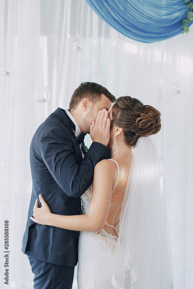 A young and beautiful bride is standing with her husband A young and beautiful bride is standing with her husband