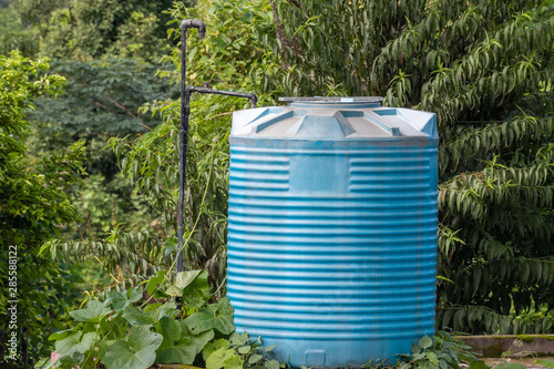 Konstfotografi Blue Water Tank covered with trees and Plants.