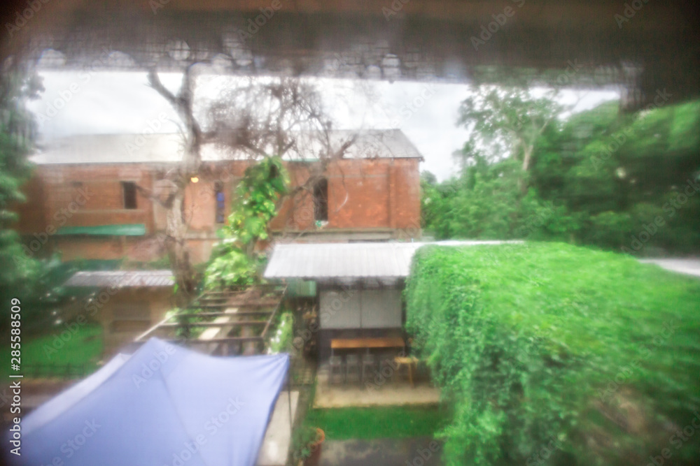 Blurred background view from the bedroom window, where there is rain outside and see the green garden fading, cool weather on holiday days. Blurred background view from the bedroom window, where there is rain outside and see the green garden fading, cool weather on holiday days.