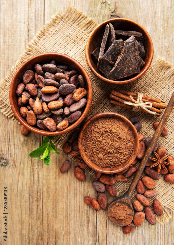 Natural cocoa powder, chocolate and cocoa beans on a wooden background Natural cocoa powder, chocolate and cocoa beans on a wooden background