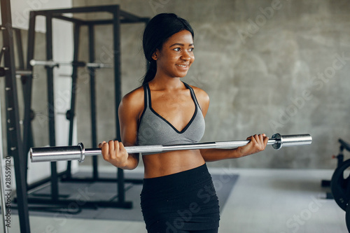 Beautiful black girl in the gym. A woman in a gray top © hetmanstock2