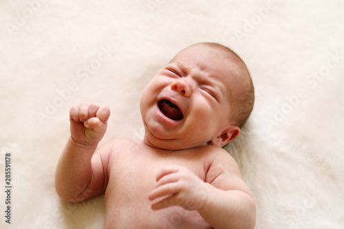 Φωτογραφία One month baby is crying with compressed fists.