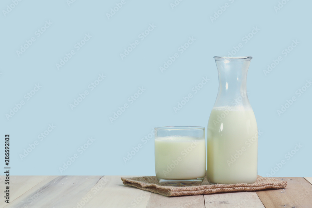 A bottle of rustic milk and glass of milk on a wooden table A bottle of rustic milk and glass of milk on a wooden table