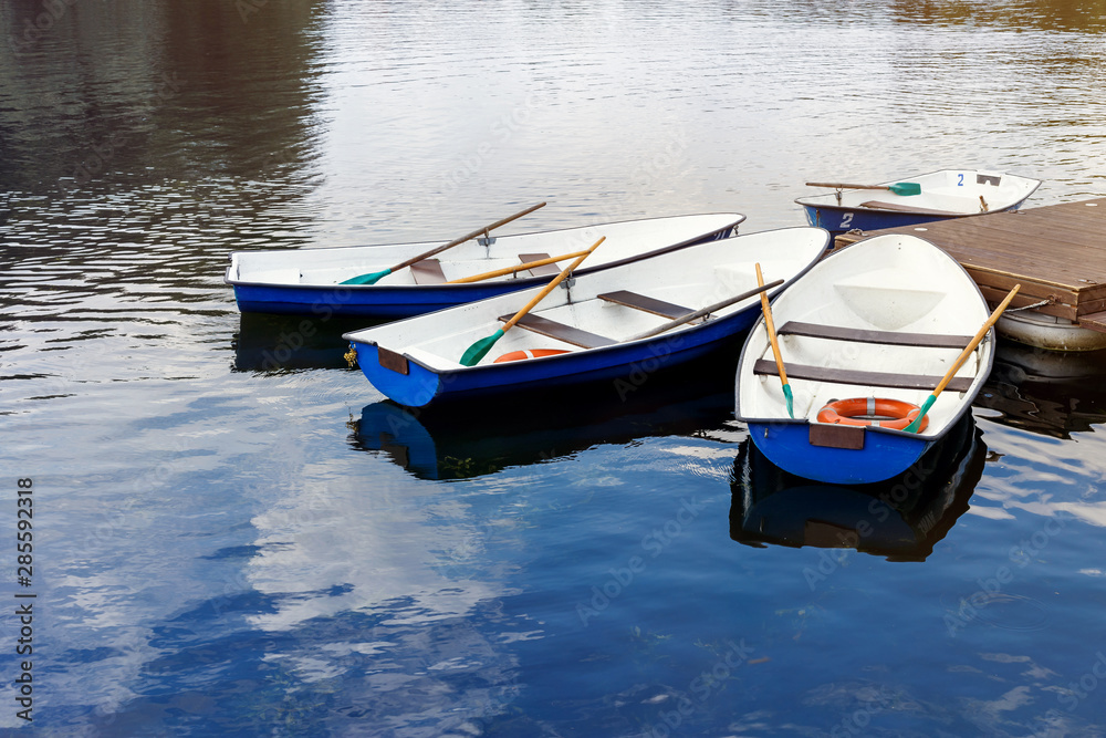 Four boats on the river. Blue old boats at the pier. Boats with oars.