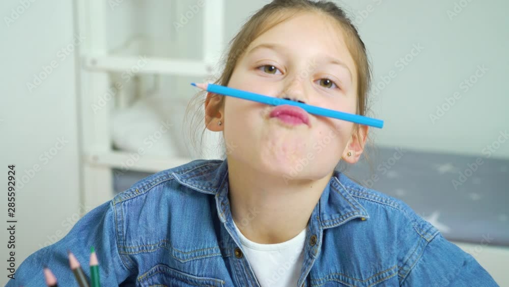 funny girl looking at camera and making faces with colored pencils as moustache funny girl looking at camera and making faces with colored pencils as moustache