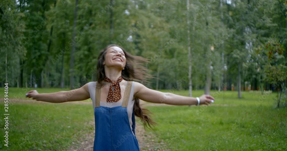 hipster girl enjoying a walk in the Park. Portrait of a young happy girl in overalls dancing and enjoying life. Carefree concept. Slow motion. hipster girl enjoying a walk in the Park. Portrait of a young happy girl in overalls dancing and enjoying life. Carefree concept. Slow motion.