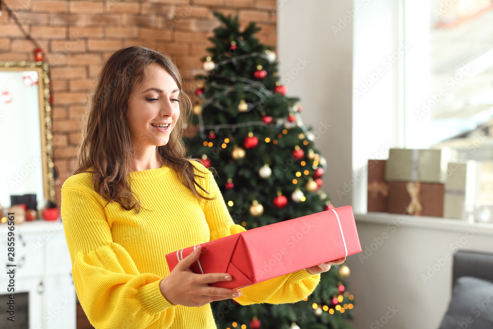 Happy young woman with Christmas gift at home Happy young woman with Christmas gift at home