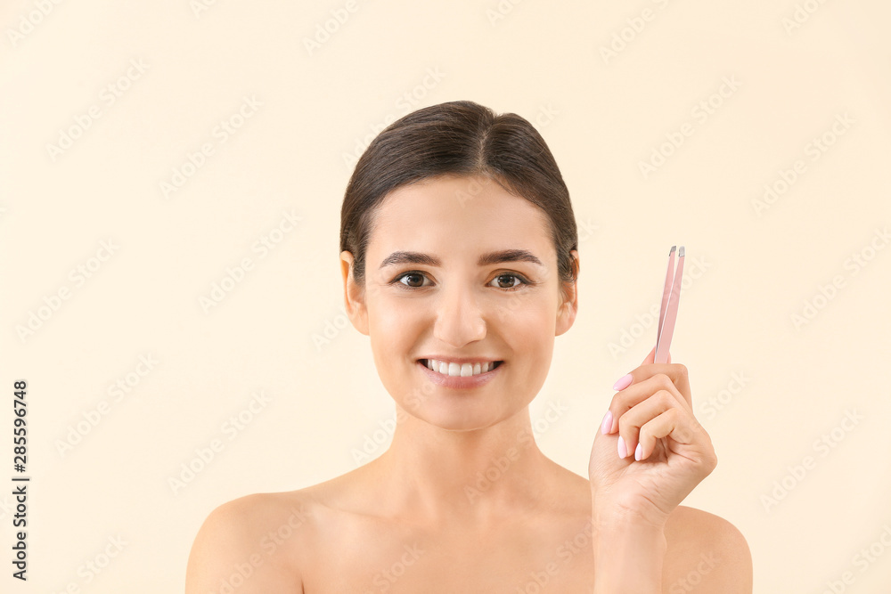 Young woman with tweezers on light background Young woman with tweezers on light background