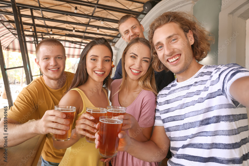 Friends taking selfie while drinking fresh beer in pub