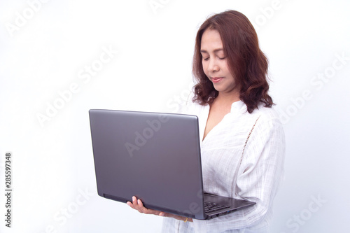 Beautiful woman holding a laptop while posing against a white background