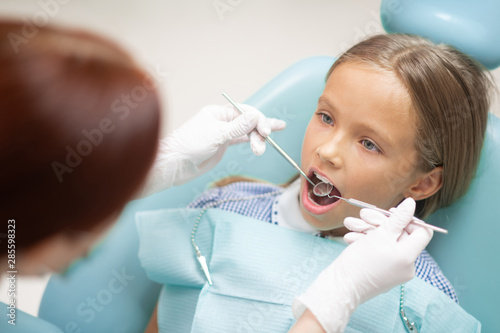 Dark-haired girl opening mouth while visiting dentist