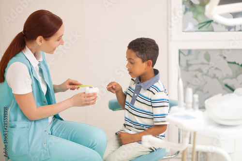 Red-haired child dentist telling boy about dental care